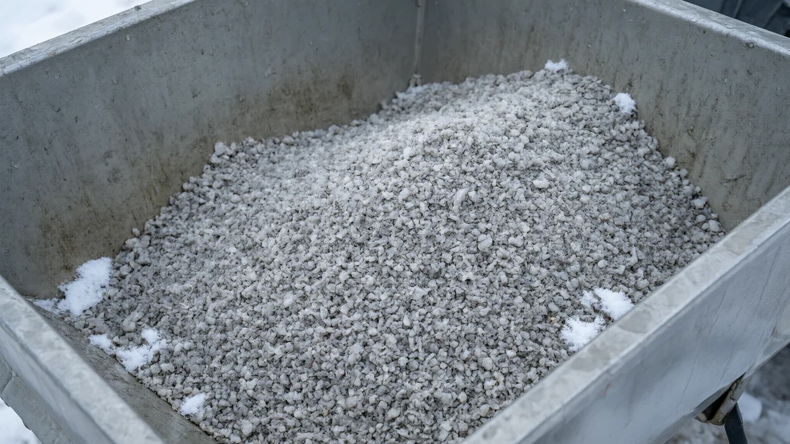 Illustrative damp salt granules in a spreader hopper for commercial de-icing