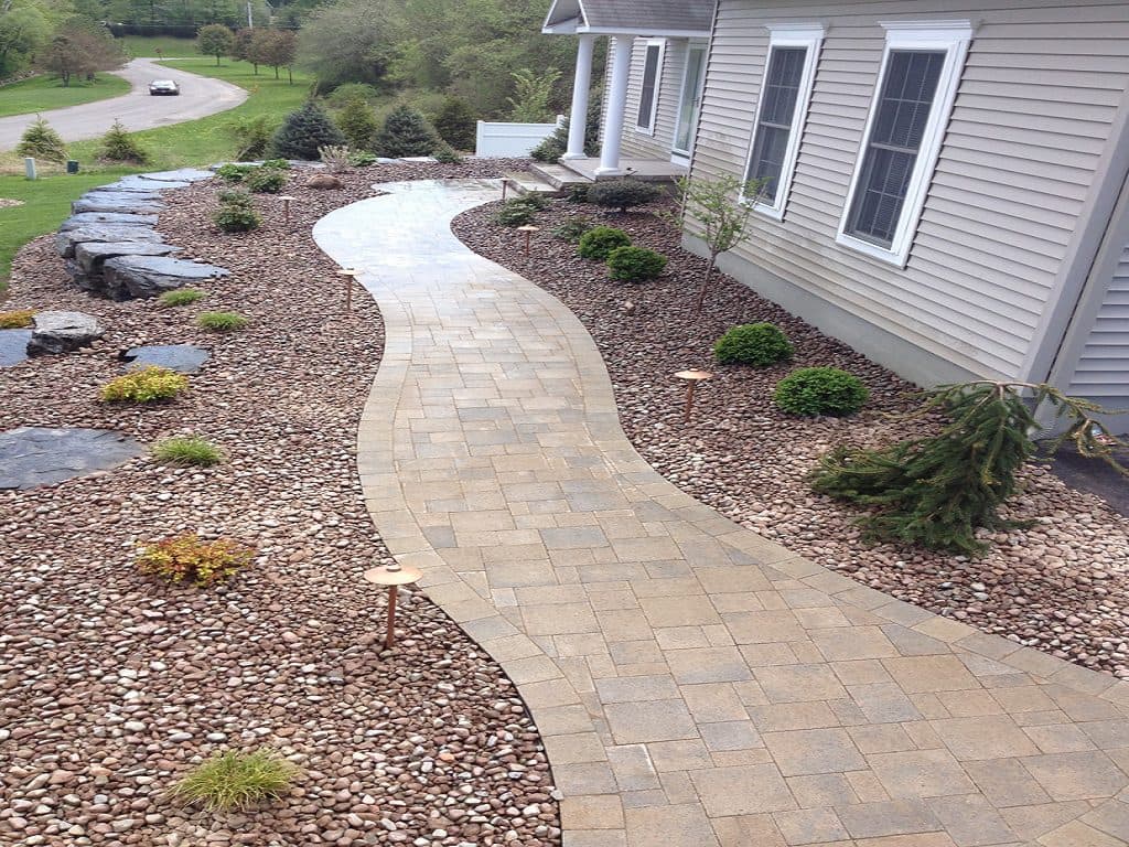 Paver walkway installation along a home with landscape lighting