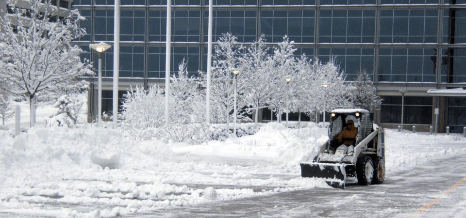 Skid steer plowing snow from a commercial office parking lot