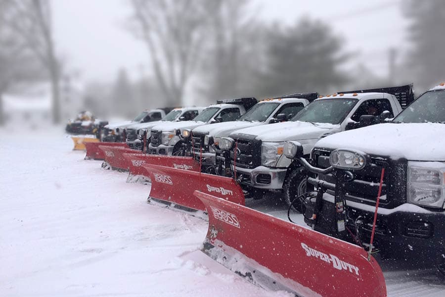 Fleet of commercial snow plow trucks staged and ready before a storm
