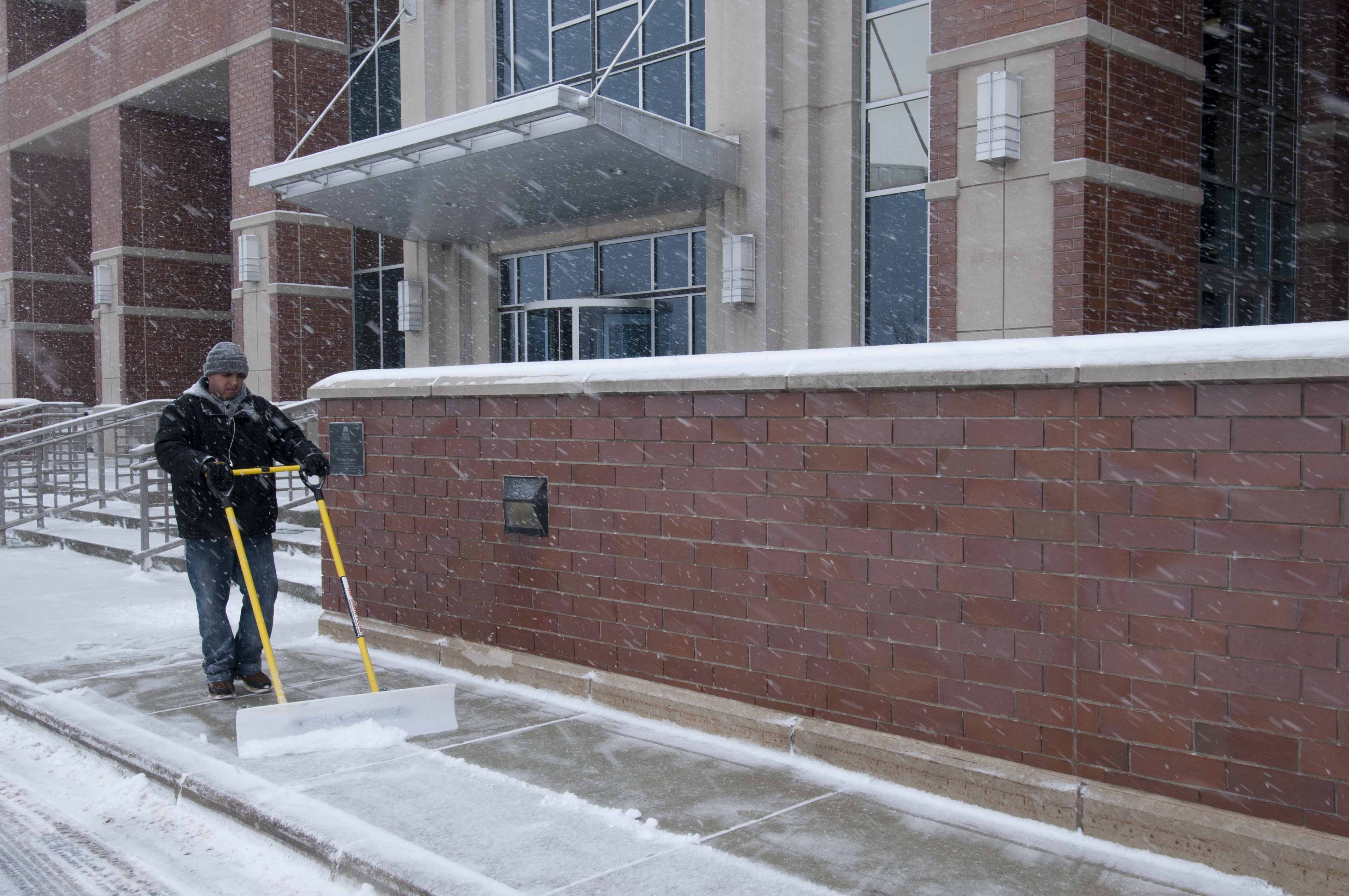 Worker shoveling snow from a sidewalk