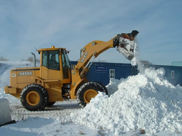 Backhoe excavating and piling snow