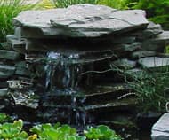 Stacked stone waterfall feature built into a landscape design